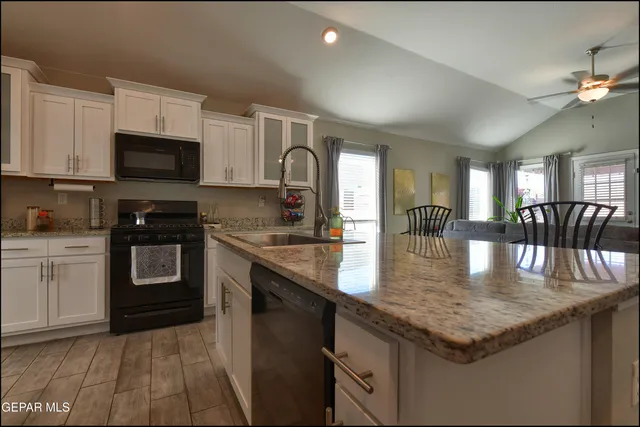 a kitchen with granite countertop a stove top oven a sink dishwasher and cabinets with wooden floor