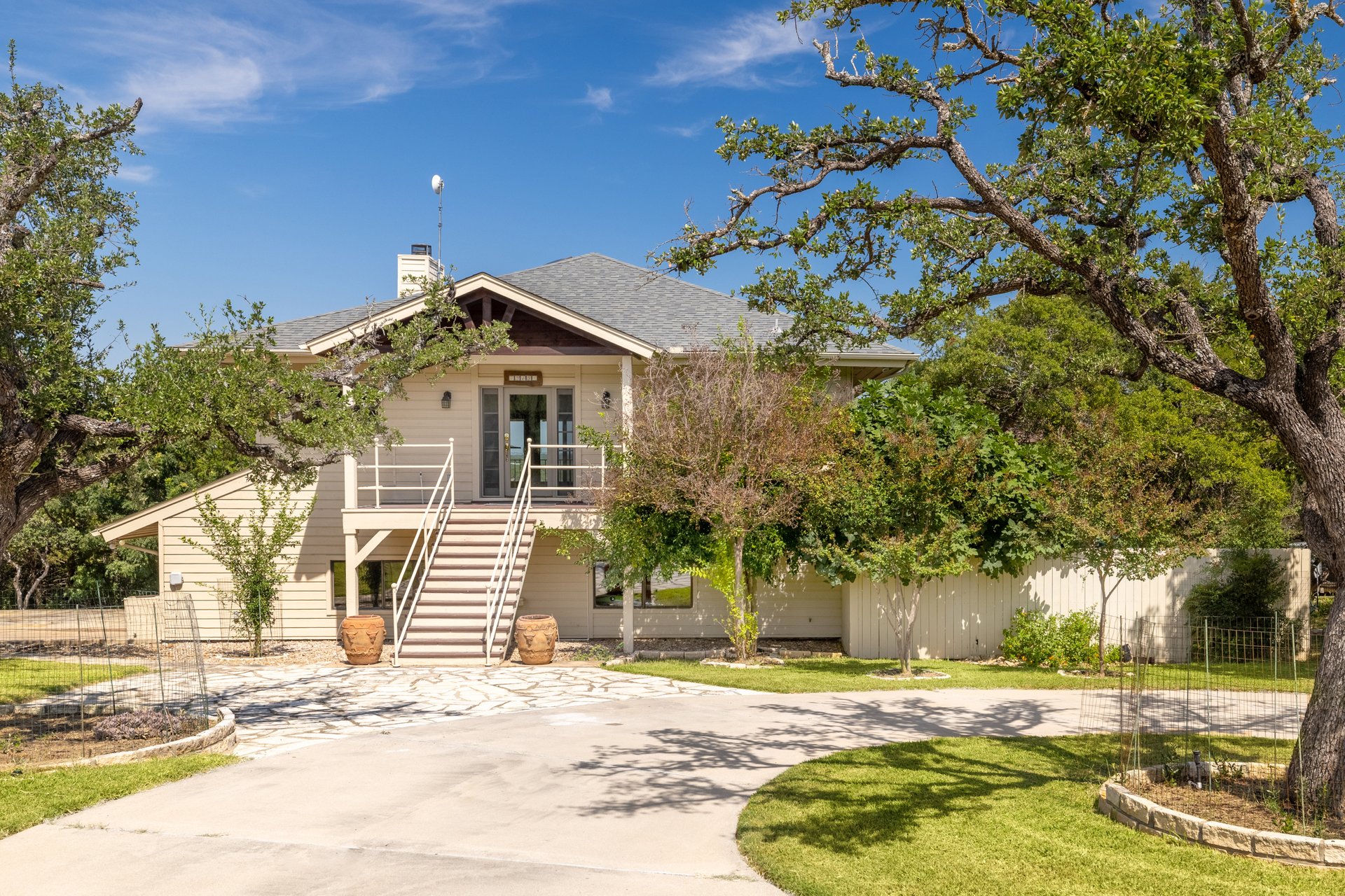 313 Kendall Road Spicewood, TX 78669 - Photo 2 of 34 View of front of property with stairway, a chimney, curved driveway, a shingled roof, and a porch