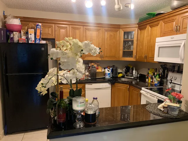 a kitchen with granite countertop white cabinets and black appliances