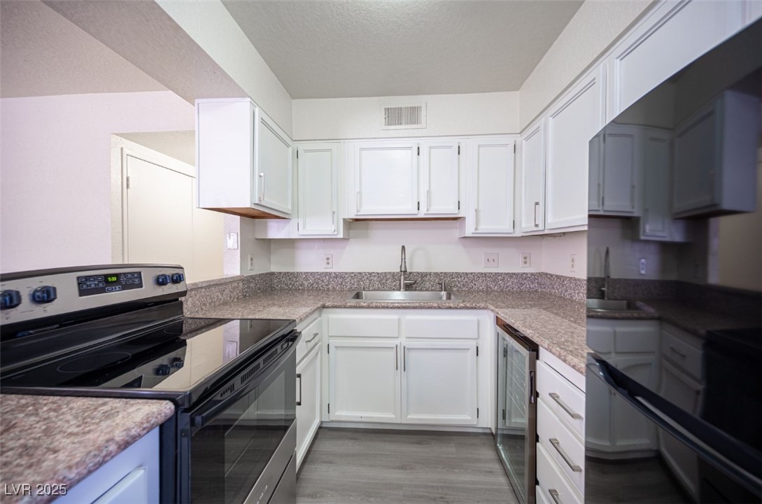5336 Mancos Court, Unit 2 Las Vegas, NV 89119 - Photo 12 of 31 Kitchen featuring electric range, freestanding refrigerator, white cabinets, beverage cooler, and a textured ceiling