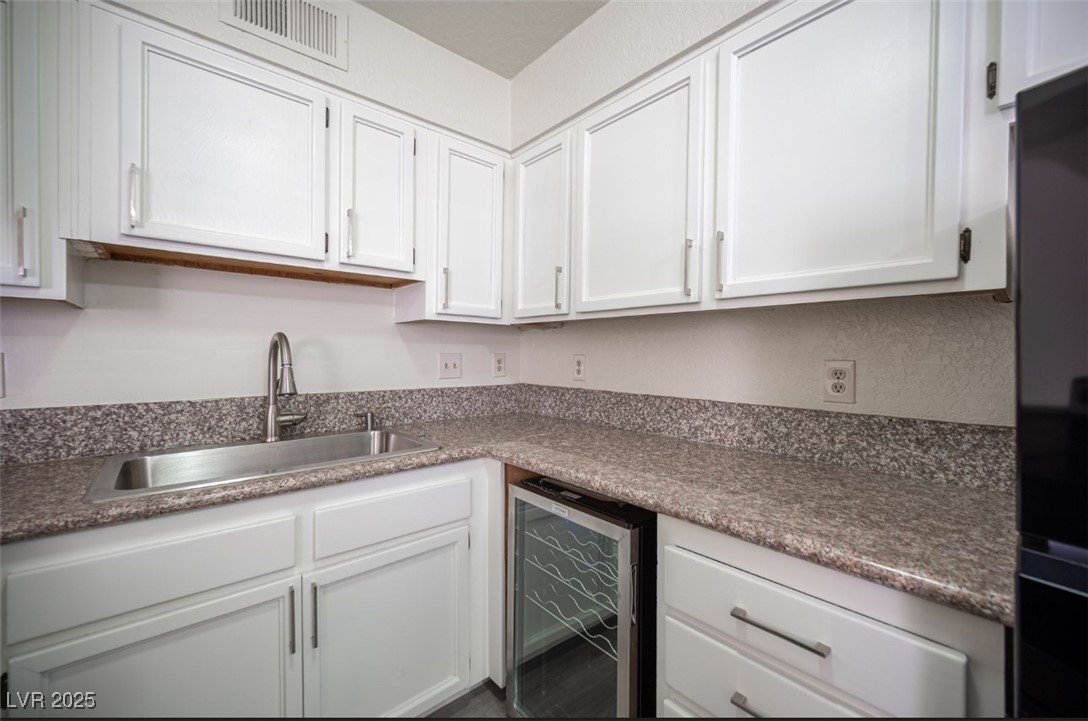 5336 Mancos Court, Unit 2 Las Vegas, NV 89119 - Photo 14 of 31 Kitchen with white cabinets, wine cooler, and freestanding refrigerator