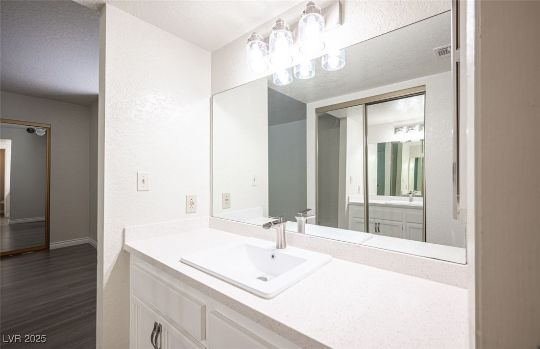 5336 Mancos Court, Unit 2 Las Vegas, NV 89119 - Photo 21 of 31 Bathroom with vanity, a textured ceiling, a chandelier, dark wood finished floors, and a textured wall