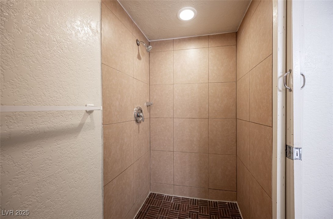 5336 Mancos Court, Unit 2 Las Vegas, NV 89119 - Photo 23 of 31 Bathroom with a textured wall, a shower stall, and a textured ceiling