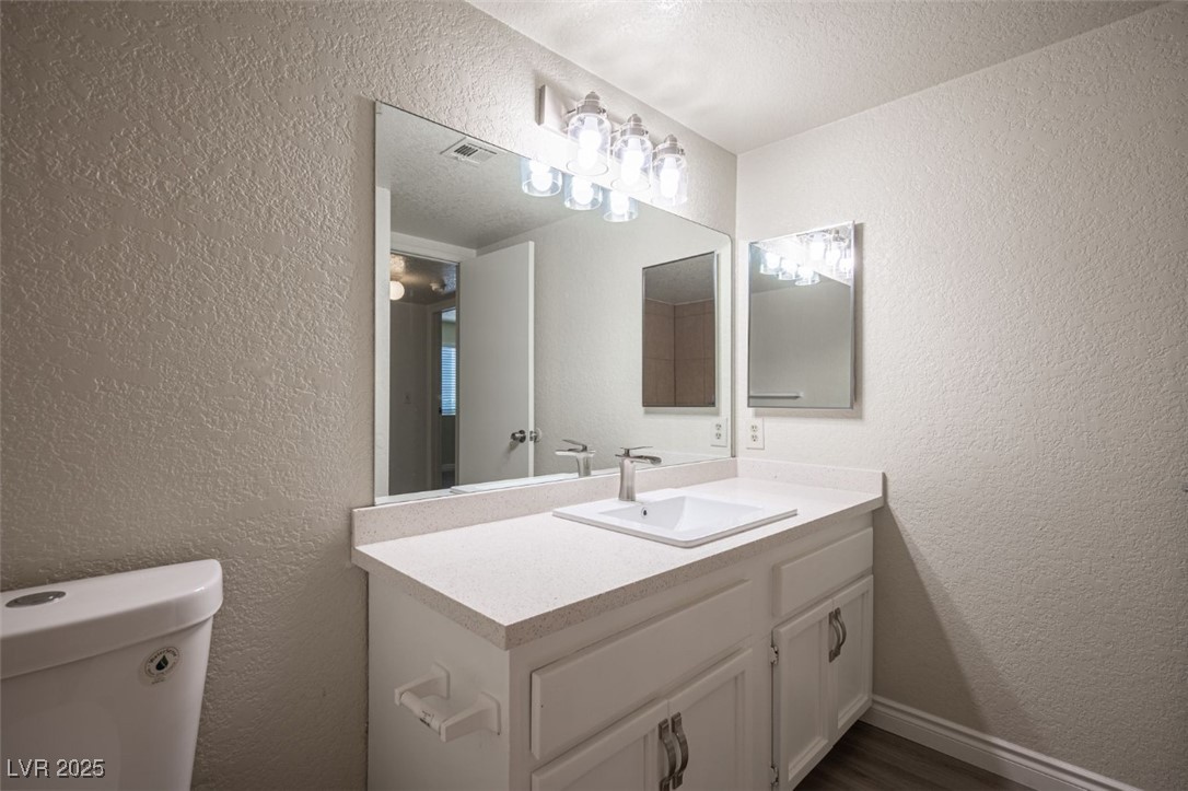 5336 Mancos Court, Unit 2 Las Vegas, NV 89119 - Photo 27 of 31 Half bathroom featuring a textured wall, vanity, and a textured ceiling