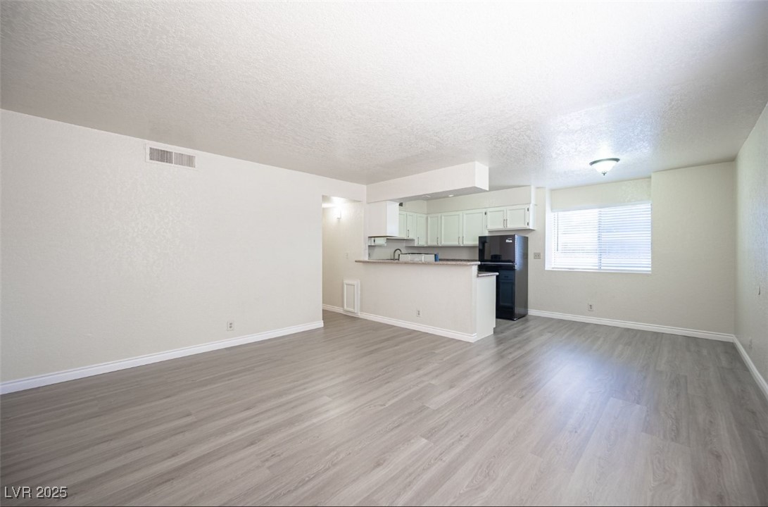 5336 Mancos Court, Unit 2 Las Vegas, NV 89119 - Photo 5 of 31 Unfurnished living room featuring a textured ceiling and light wood finished floors