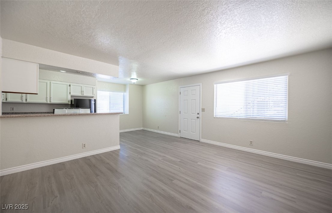 5336 Mancos Court, Unit 2 Las Vegas, NV 89119 - Photo 6 of 31 Unfurnished living room featuring a textured ceiling and dark wood finished floors