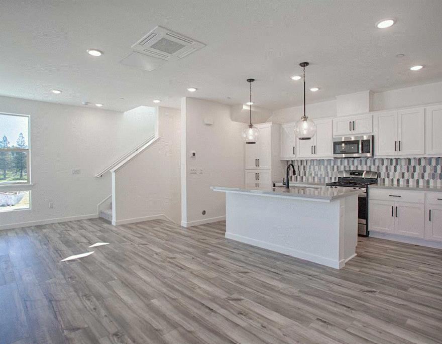 6705 Optimum Loop San Jose, CA 95119 - Photo 7 of 19 a kitchen with stainless steel appliances kitchen island granite countertop a stove a refrigerator and white cabinets with wooden floor