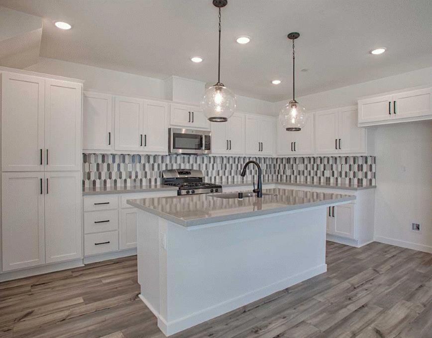 6705 Optimum Loop San Jose, CA 95119 - Photo 8 of 19 a kitchen with kitchen island white cabinets stainless steel appliances a sink and wooden floor