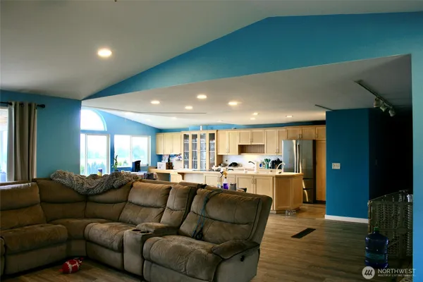 a living room with furniture kitchen view and a wooden floor