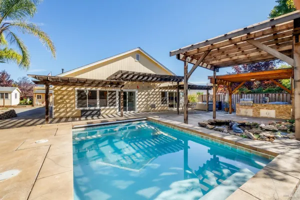 a view of a house with backyard swimming pool and sitting area