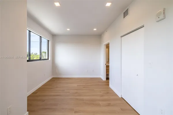 an empty room with wooden floor and windows
