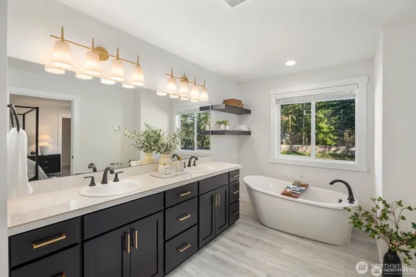 a bathroom with a tub double vanity sink and a large mirror