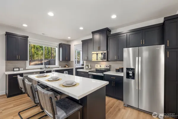 a kitchen with kitchen island a refrigerator a sink a stove and chairs