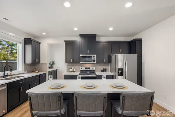 a kitchen with stainless steel appliances granite countertop a sink a stove a refrigerator and cabinets