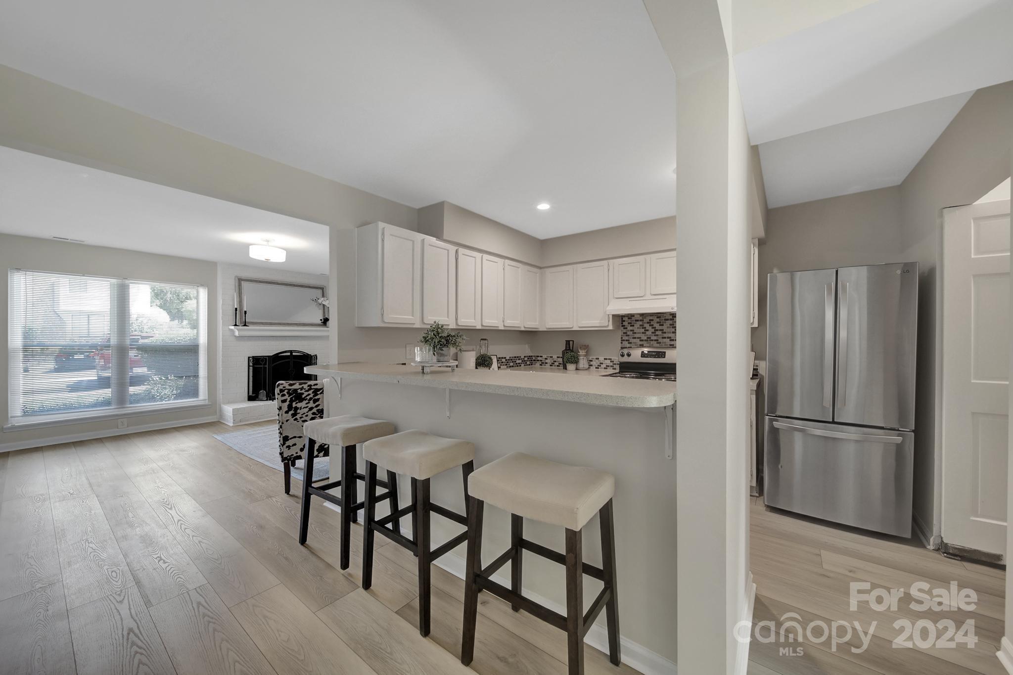 10943 Carmel Crossing Road Charlotte, NC 28226 - Photo 3 of 28 a kitchen with stainless steel appliances granite countertop a dining table chairs refrigerator and cabinets