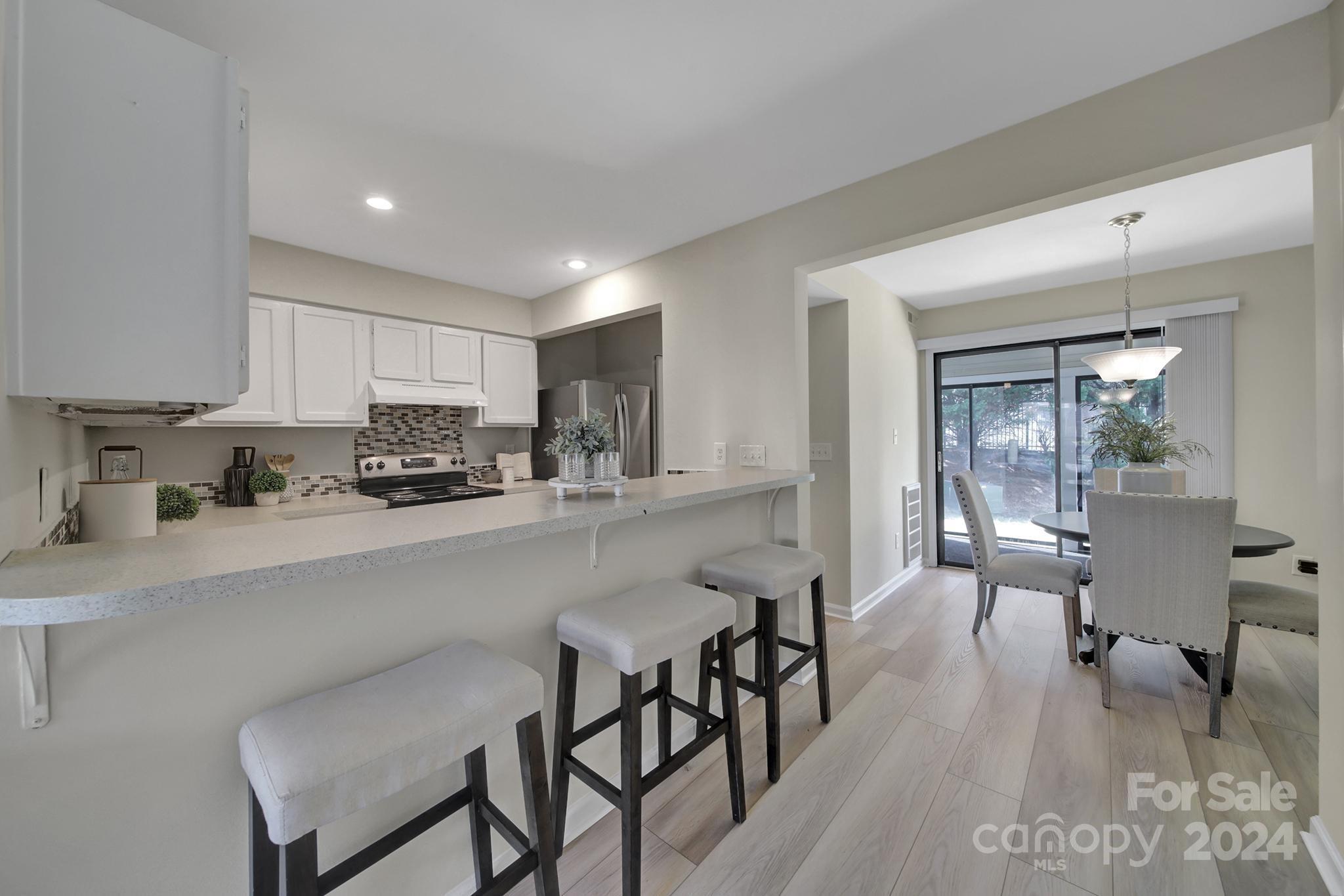10943 Carmel Crossing Road Charlotte, NC 28226 - Photo 4 of 28 a kitchen with stainless steel appliances a table and chairs in it