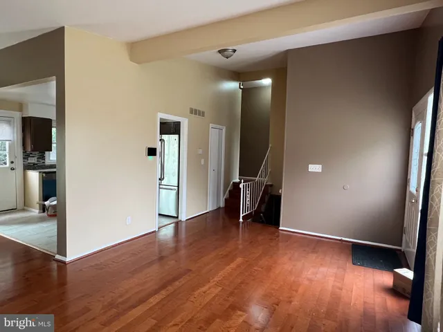 a view of a hallway with wooden floor and a living room