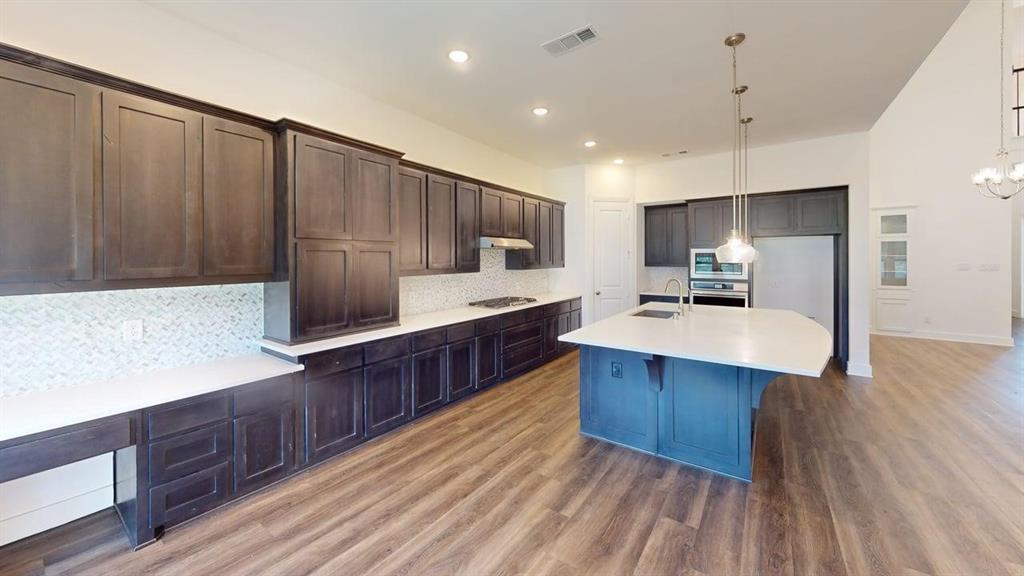 9628 Boulder Pt Road Oak Point, TX 75068 - Photo 5 of 35 Spacious kitchen featuring dark wood-finish cabinetry, light countertops, and a full tile backsplash
