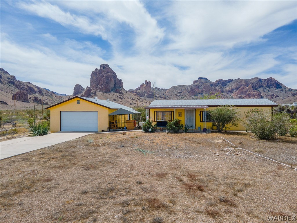 2465 Egar Road Golden Valley, AZ 86413 - Photo 64 of 98 The property features a yellow exterior and a concrete driveway leading to a garage with a white door