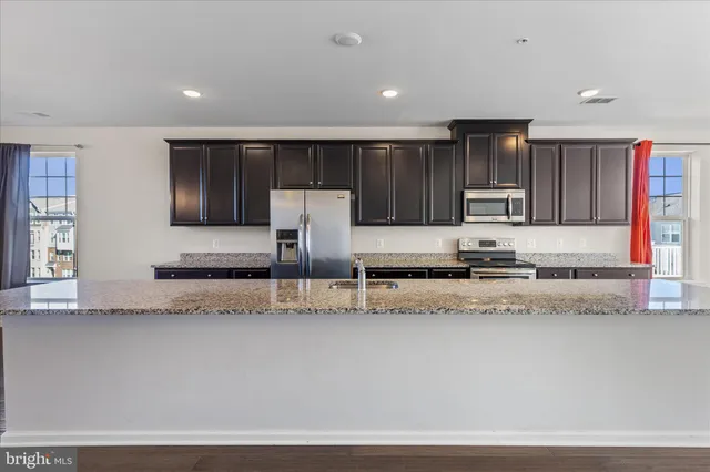 a kitchen with stainless steel appliances granite countertop a sink a stove and a refrigerator