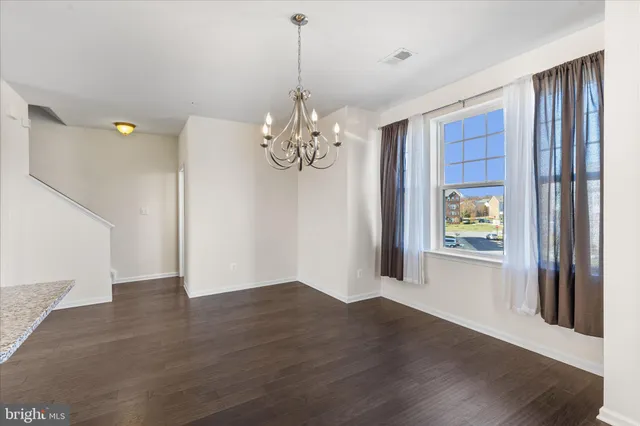 a view of a hallway with wooden floor and a chandelier