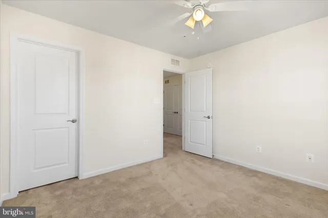 an empty room with a chandelier fan and closet area