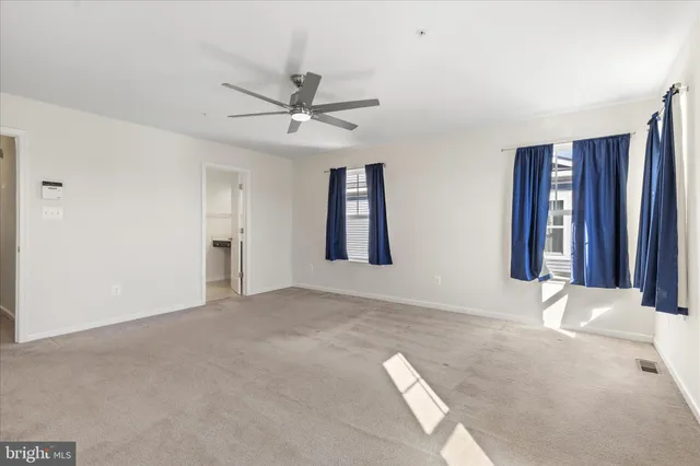 a view of an empty room with window and chandelier fan