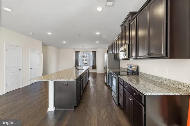an open kitchen with granite countertop stainless steel appliances and wooden floor