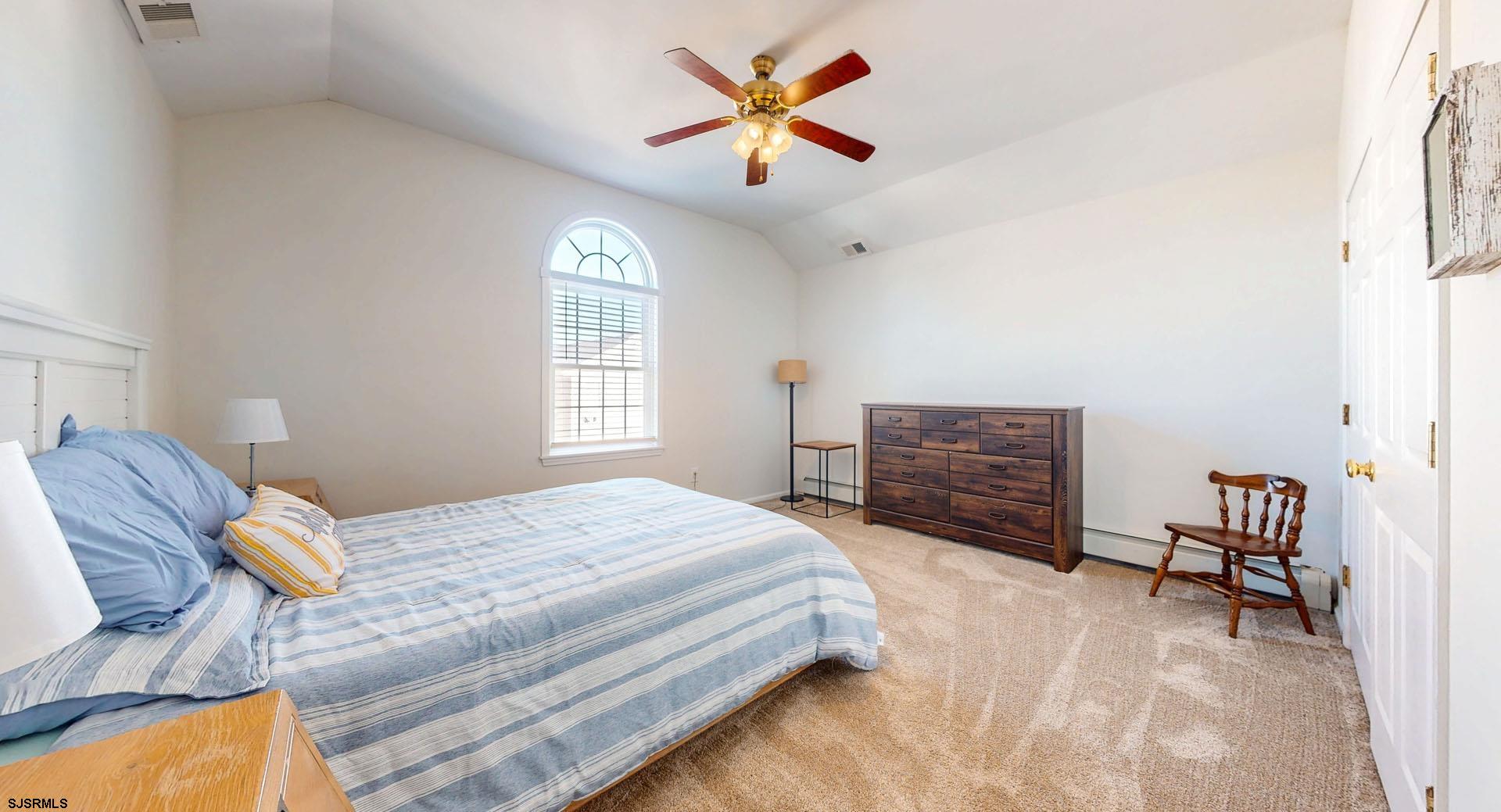 39 Spruce Road Ocean City, NJ 08226 - Photo 33 of 51 a bedroom with a bed a chandelier and a dresser
