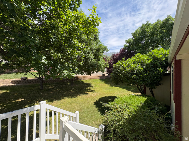 595 Meadowlark Road Orem, UT 84097 - Photo 80 of 87 Expansive backyard featuring a manicured lawn, mature trees, tiered landscaping with stone retaining walls, and surrounding greenery