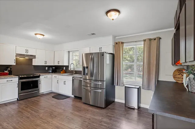 a kitchen with granite countertop a refrigerator stove top oven and sink