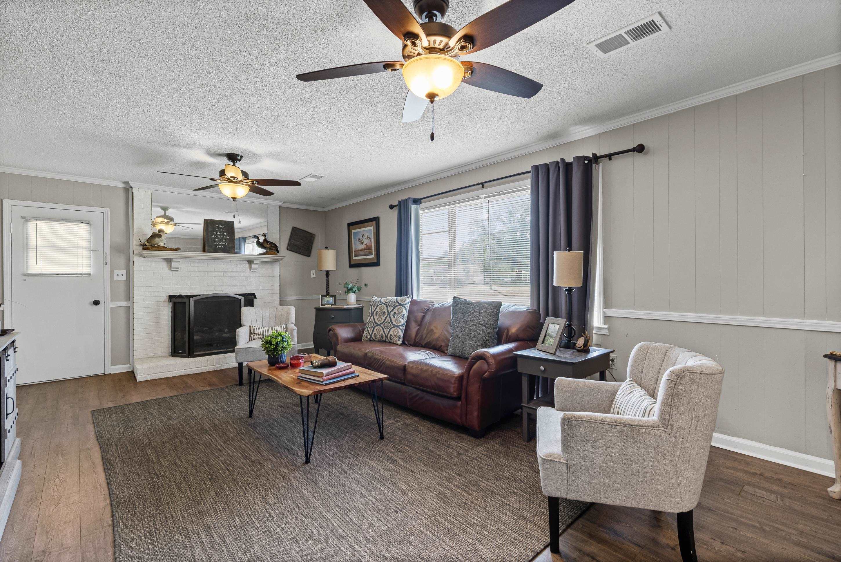 2805 Slayden Road Moscow, TN 38057 - Photo 19 of 28 Living room featuring crown molding, wood finished floors, a brick fireplace, a textured ceiling, and ceiling fan
