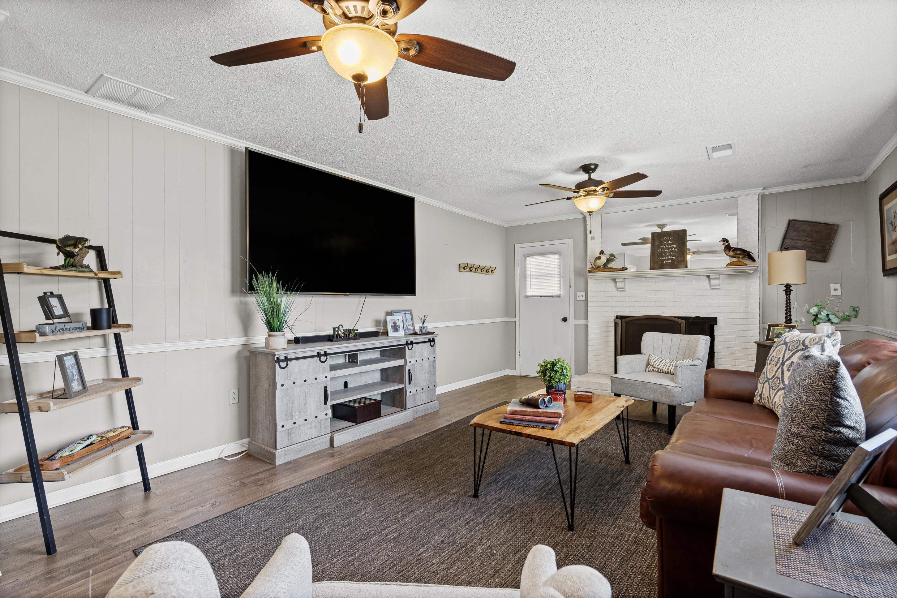 2805 Slayden Road Moscow, TN 38057 - Photo 20 of 28 Living room with ornamental molding, wood walls, a textured ceiling, wood finished floors, and a brick fireplace