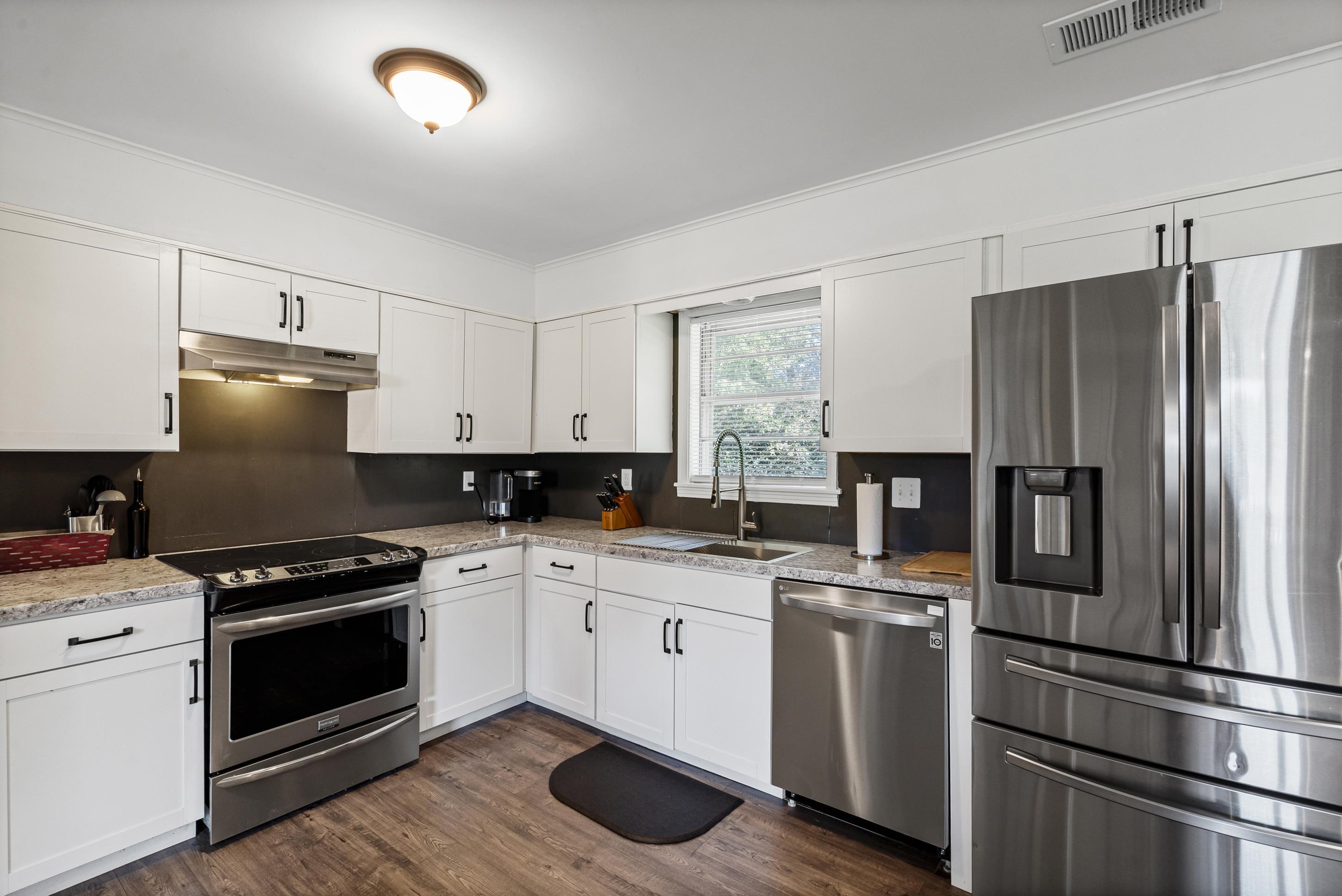 2805 Slayden Road Moscow, TN 38057 - Photo 2 of 28 Kitchen featuring appliances with stainless steel finishes, white cabinetry, dark wood-type flooring, under cabinet range hood, and crown molding