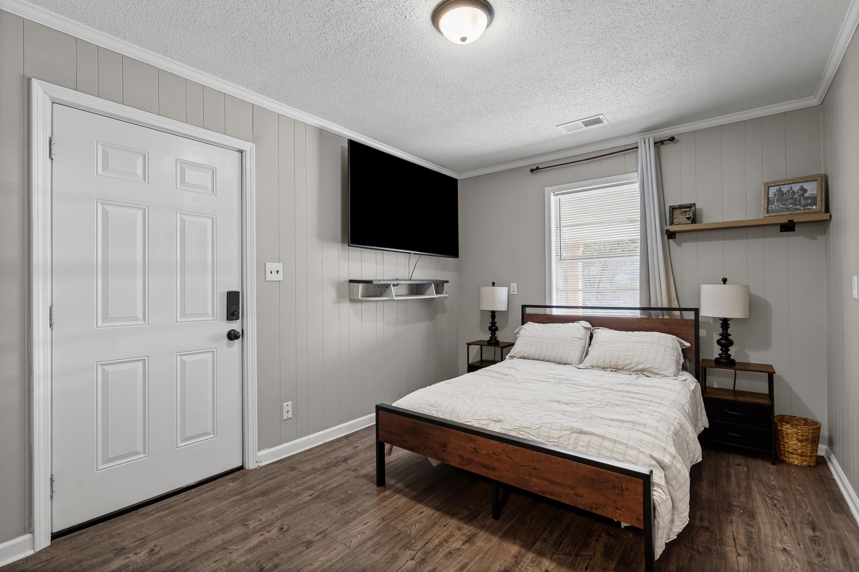 2805 Slayden Road Moscow, TN 38057 - Photo 22 of 28 Bedroom featuring crown molding, dark wood-type flooring, wooden walls, and a textured ceiling