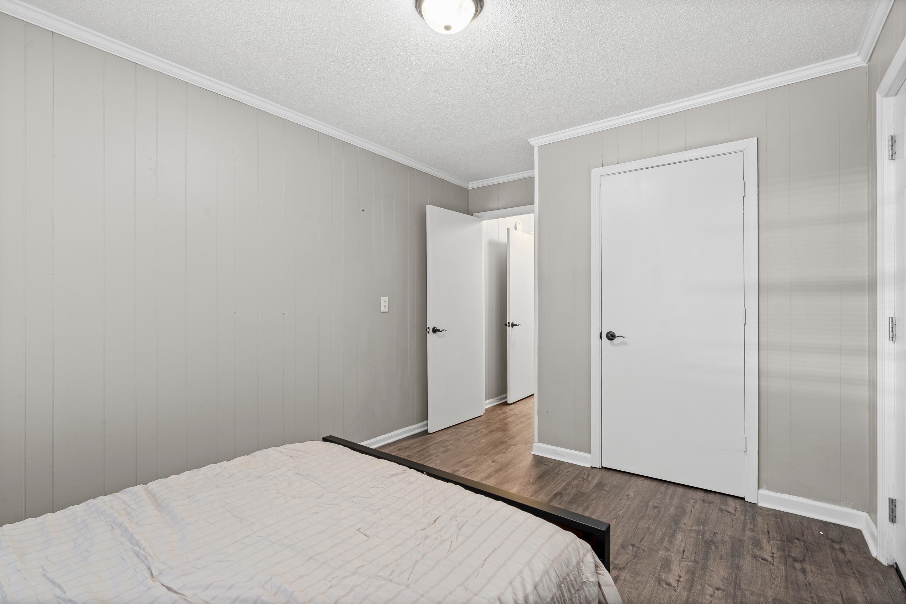 2805 Slayden Road Moscow, TN 38057 - Photo 23 of 28 Bedroom featuring crown molding, dark wood finished floors, a textured ceiling, and wood walls