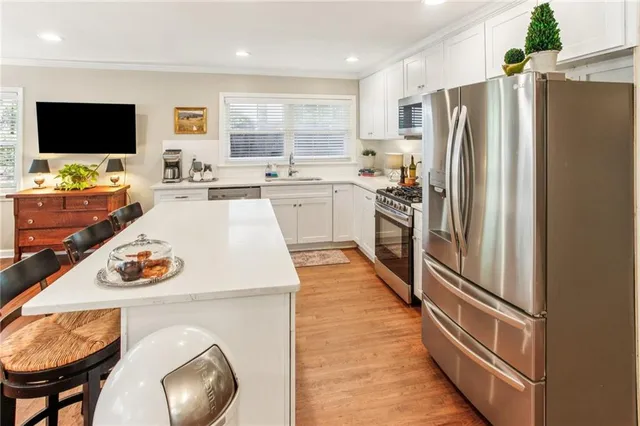 a kitchen with stainless steel appliances granite countertop a refrigerator a stove a microwave and a dining table with wooden floor