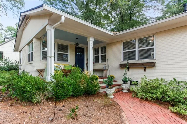 a view of a house with potted plants and a table and chair