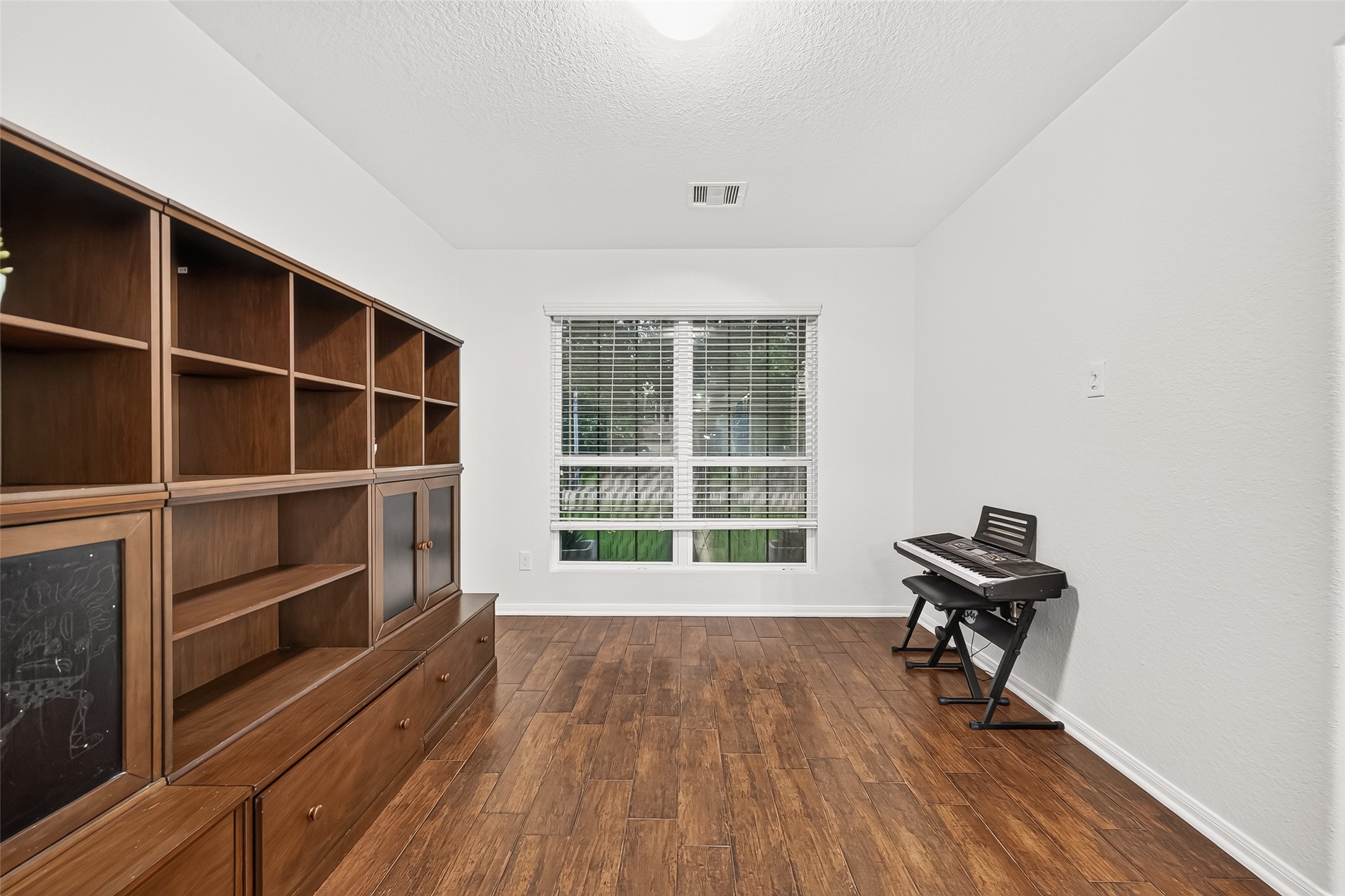 3155 View Valley Trail Katy, TX 77493 - Photo 7 of 50 A versatile bonus room flooded with natural light from a large window, complemented by rich hardwood-style flooring.
