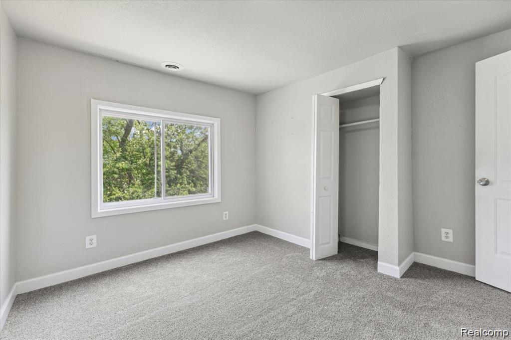 3140 Moore Street Inkster, MI 48141 - Photo 10 of 18 Bright interior space featuring a window with exterior tree views, neutral gray wall paint, and gray carpeting