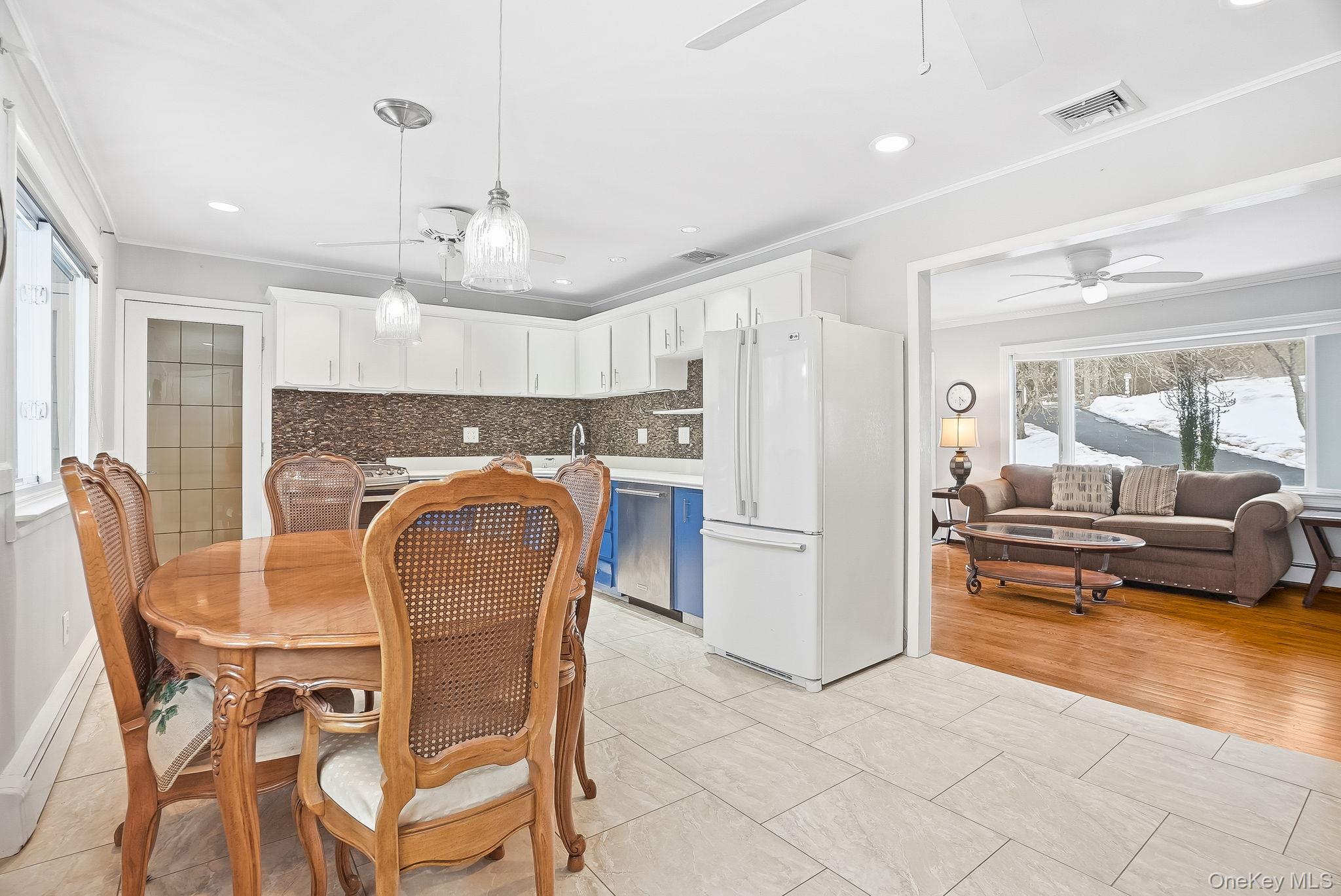 12 Lakeview Road Carmel, NY 10512 - Photo 5 of 31 a kitchen with stainless steel appliances a refrigerator a stove a dining table and chairs with wooden floor