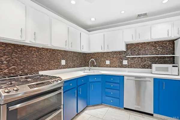 a kitchen with granite countertop a sink stainless steel appliances and white cabinets
