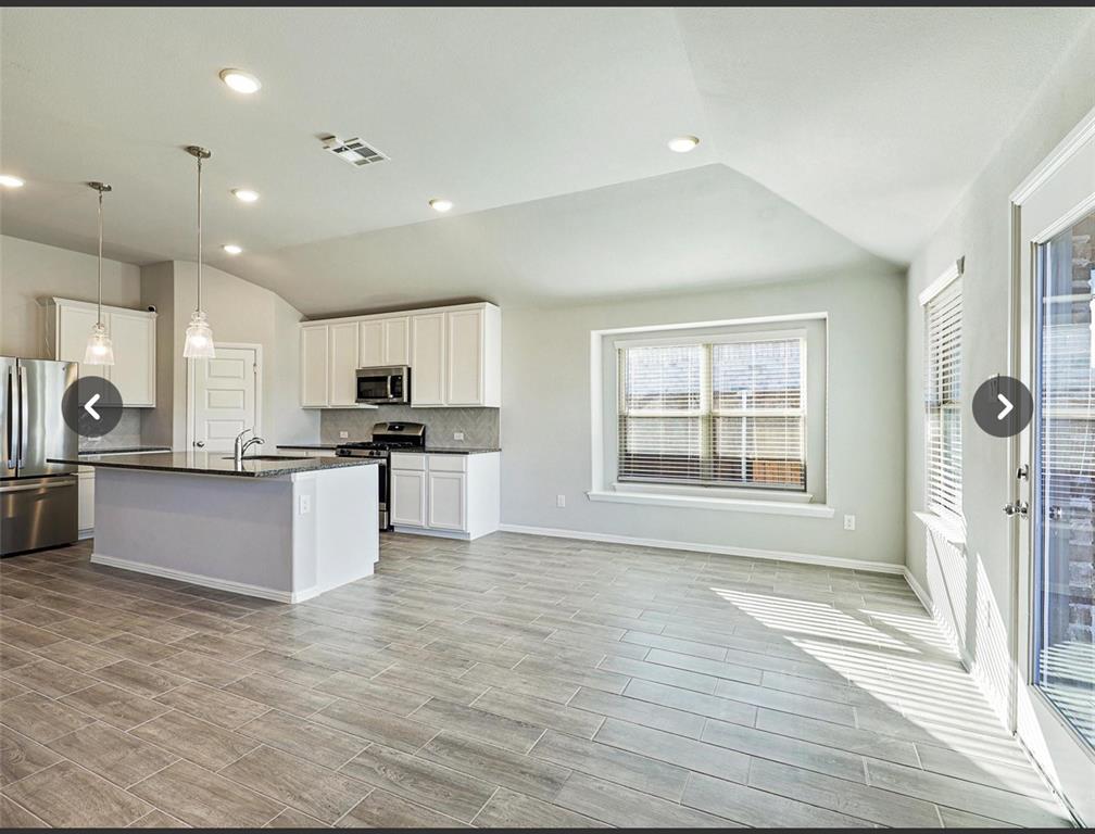 14219 Aberavon Drive Pilot Point, TX 76258 - Photo 11 of 25 a large kitchen with stainless steel appliances kitchen island granite countertop a stove a sink a refrigerator white cabinets and wooden floor