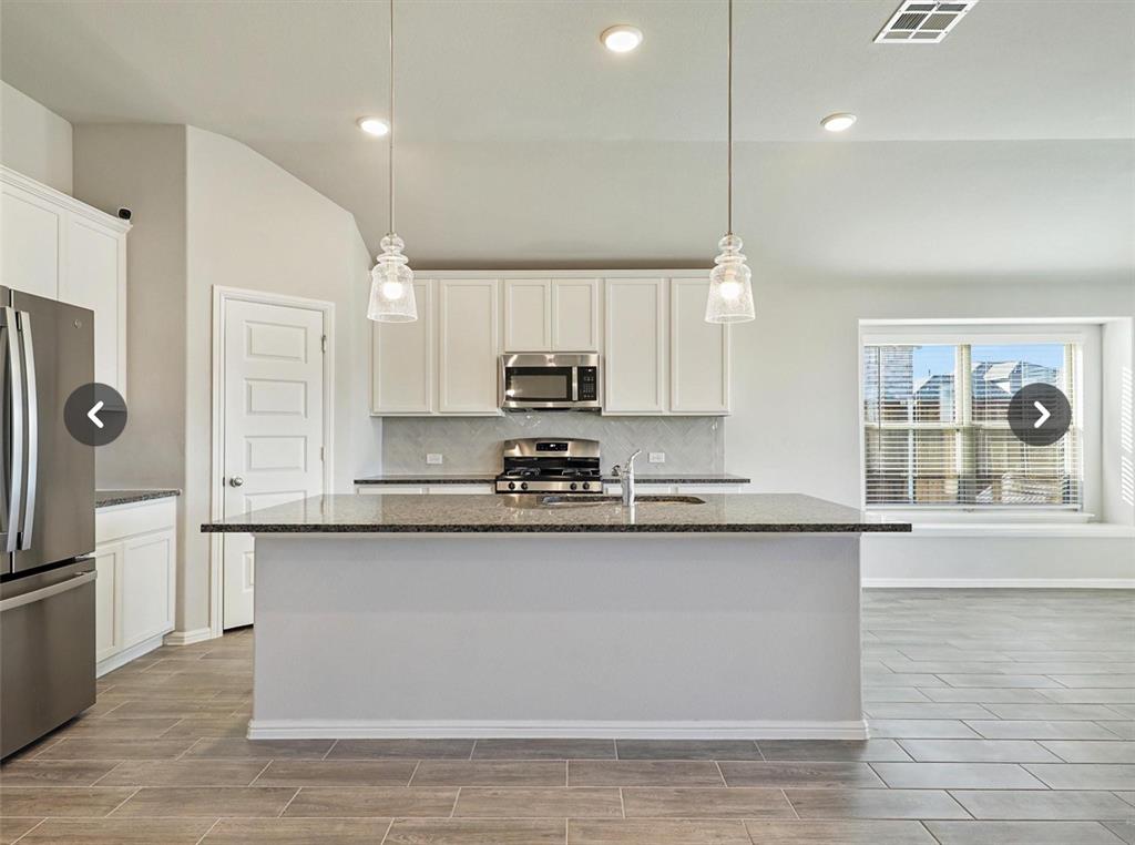 14219 Aberavon Drive Pilot Point, TX 76258 - Photo 10 of 25 a large kitchen with stainless steel appliances granite countertop a stove a sink dishwasher and a refrigerator with wooden floor