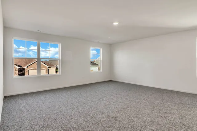 an empty room with windows and ceiling fan