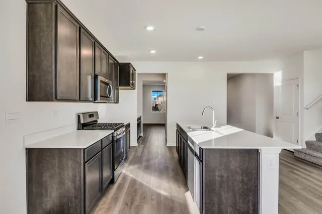 a kitchen with stainless steel appliances granite countertop a sink a stove and a refrigerator