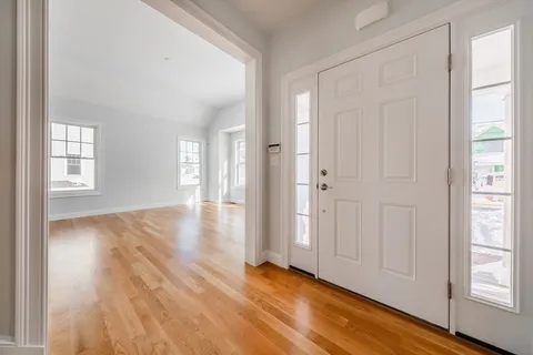 an empty room with wooden floor and windows with curtains