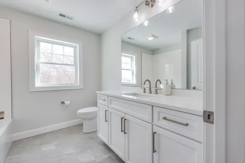 a bathroom with double vanity sink a toilet and a window