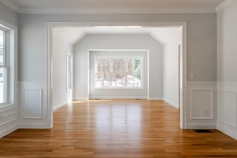 a view of an empty room with wooden floor and a window