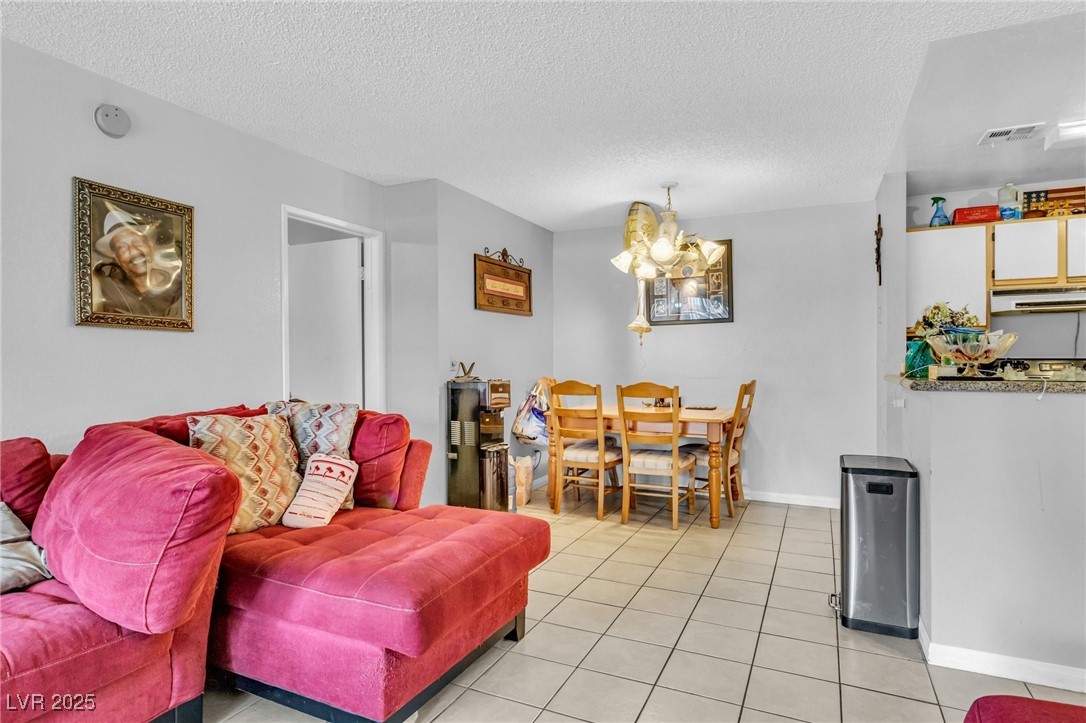 2200 South Fort Apache Road, Unit 1007 Las Vegas, NV 89117 - Photo 8 of 30 Living room featuring light tile patterned floors, a textured ceiling, a chandelier, and visible vents